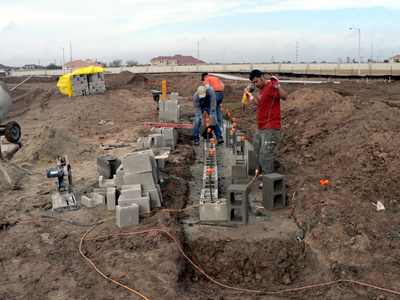 Crew laying concrete block foundation on a school site